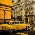 Vintage yellow taxi parked on city street with buildings and bare trees - nostalgic urban scene