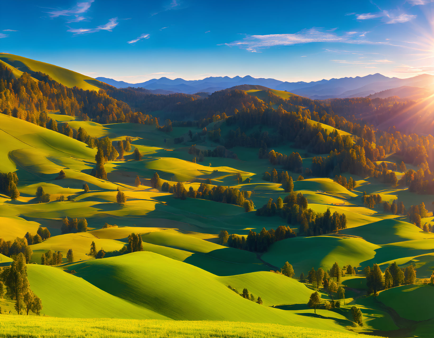 Scenic landscape with green hills, trees, mountains, and sunset sky