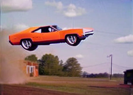 Bright Orange Muscle Car Mid-Air Against Blue Sky