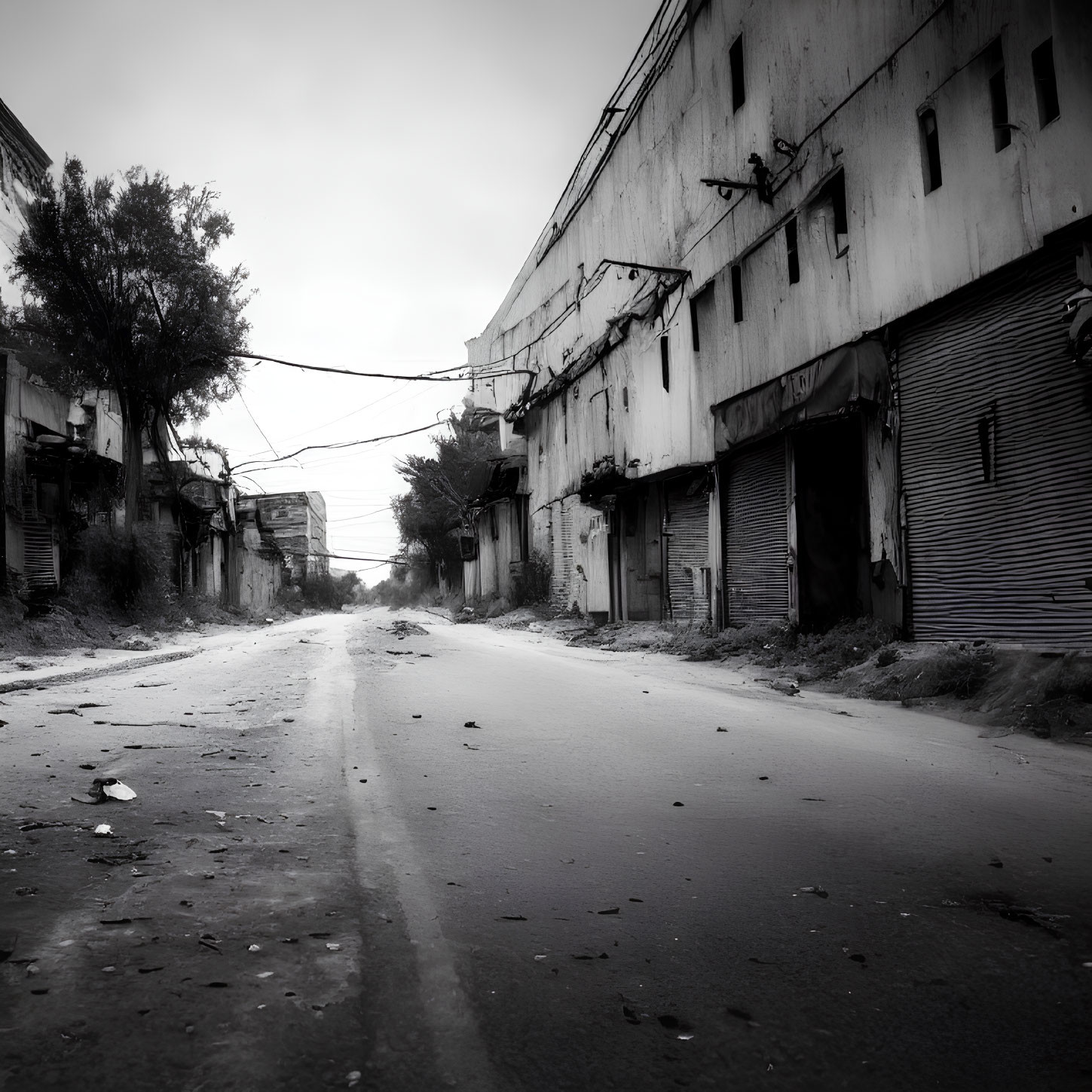 Desolate urban street with closed shops and debris under overcast skies