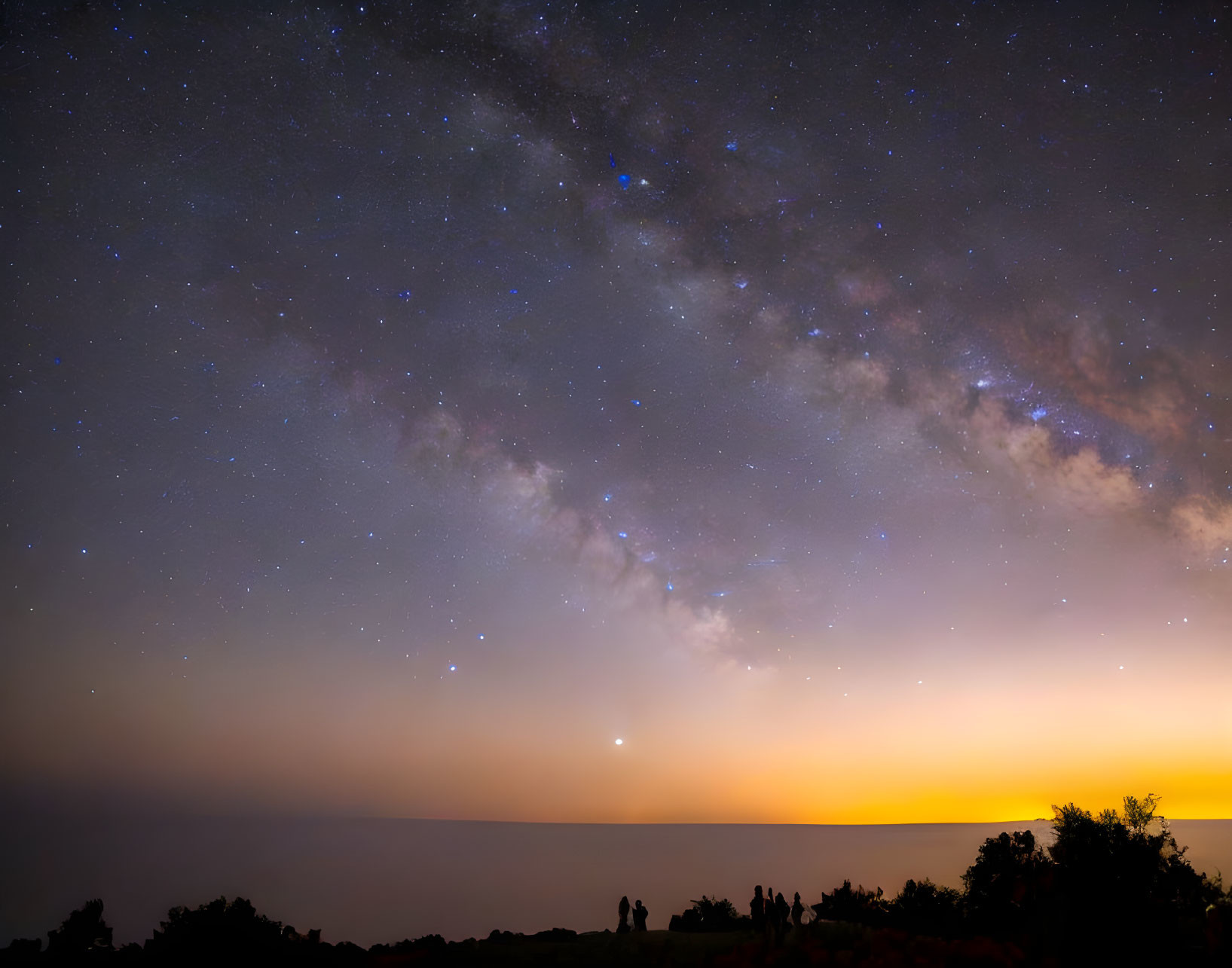 Starry night sky with Milky Way over glowing dusk horizon.