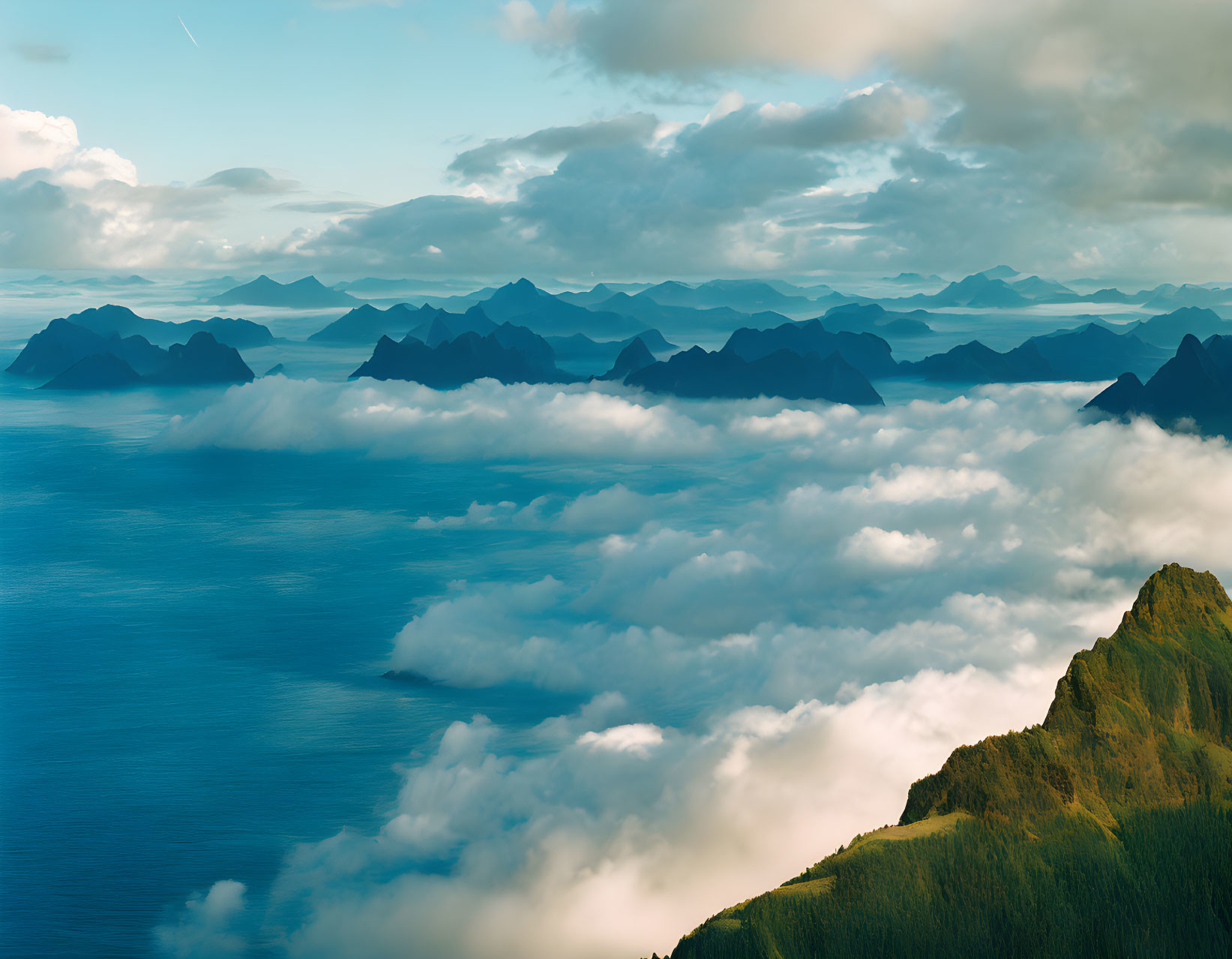 Sunlit mountain peaks above clouds overlooking ocean landscape