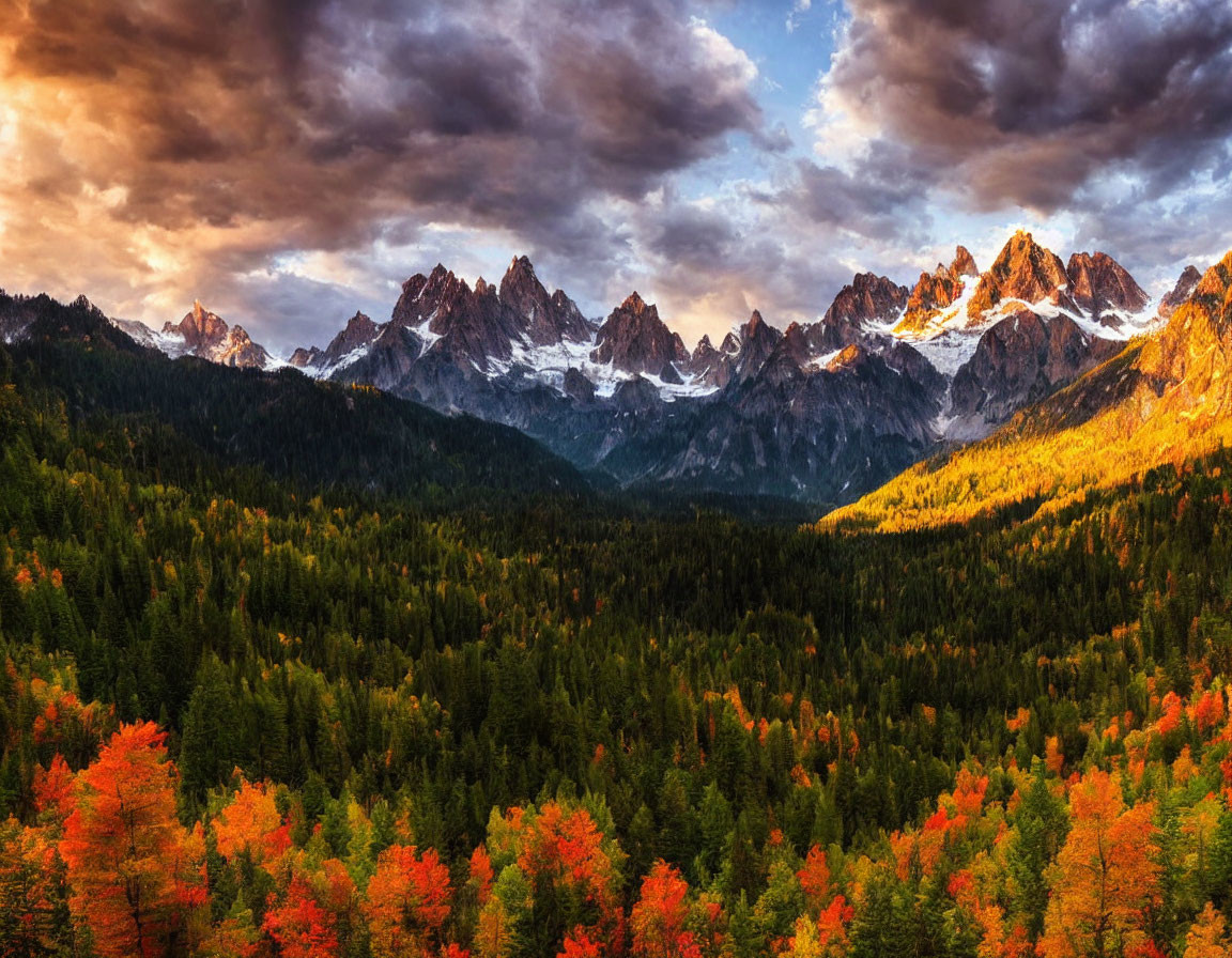 Majestic snowy mountain range and autumn forest under dramatic sunset