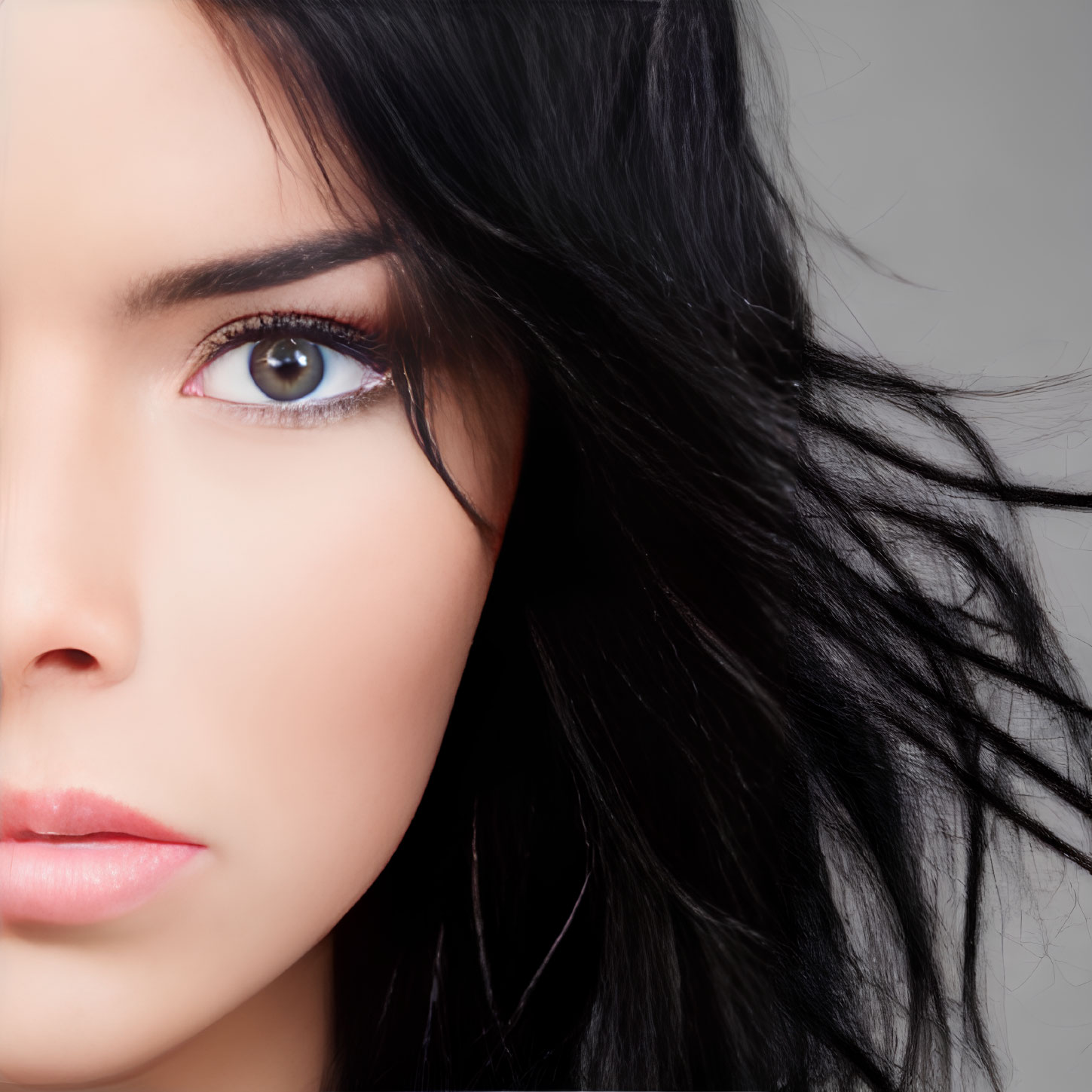 Woman with piercing blue eyes and dark hair in close-up shot with subtle makeup, wind blowing hair.