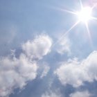 Bright sun illuminating fluffy cumulus clouds in soft blue sky