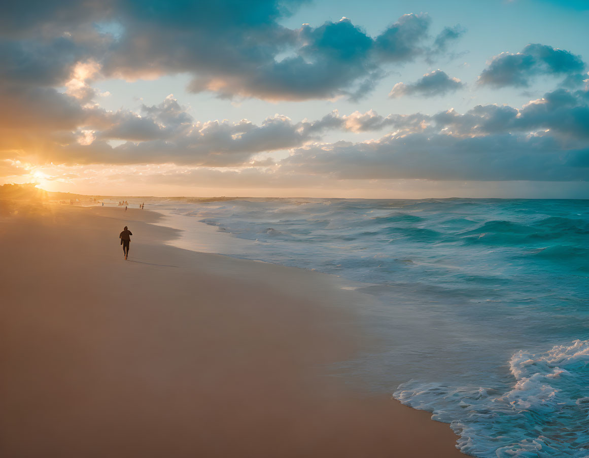 Golden sunset over beach with people, crashing waves, and dramatic sky