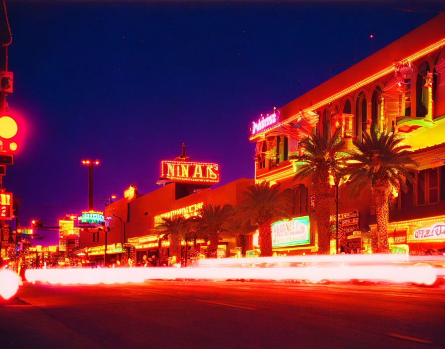 Neon signs, traffic trails, palm trees in vibrant night scene