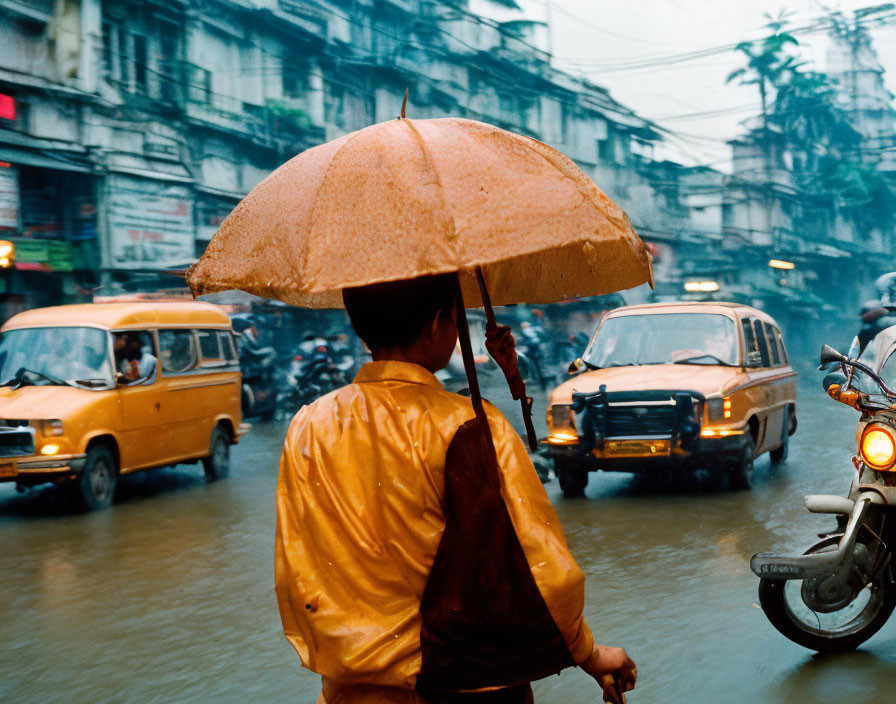 Person in Yellow Raincoat with Umbrella on Flooded Street Amid Traffic