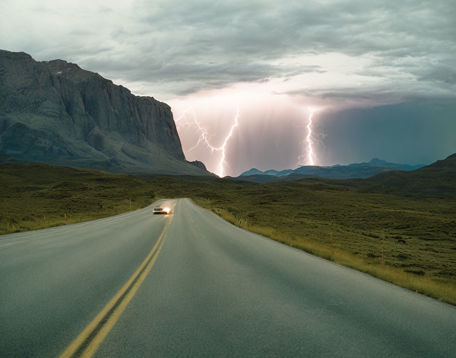 Lonely highway car driving towards distant lightning strikes under stormy sky