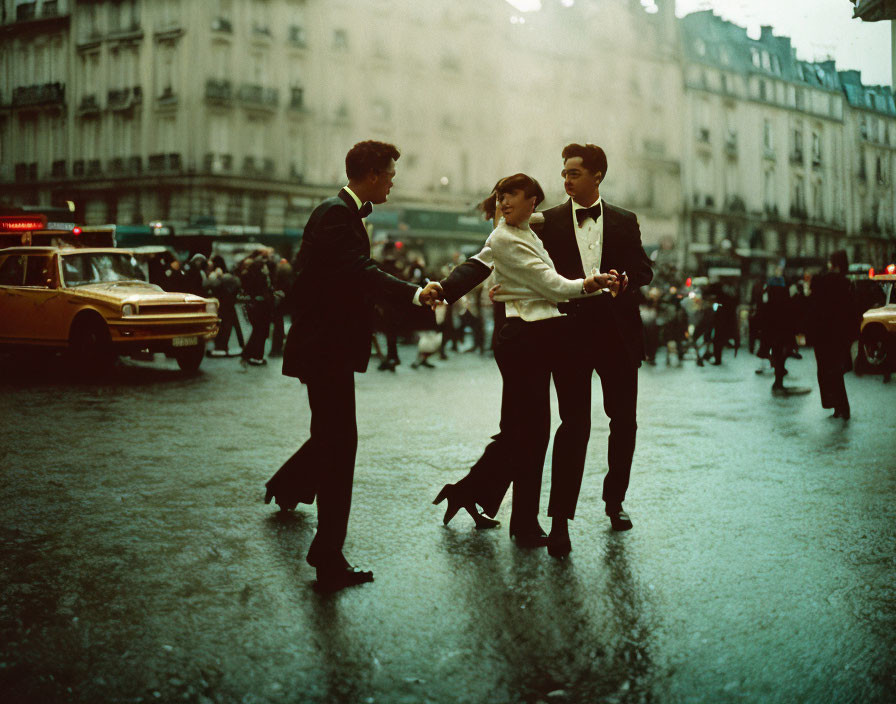 Elegantly dressed people dancing on wet urban street with vintage cars and classic city architecture.