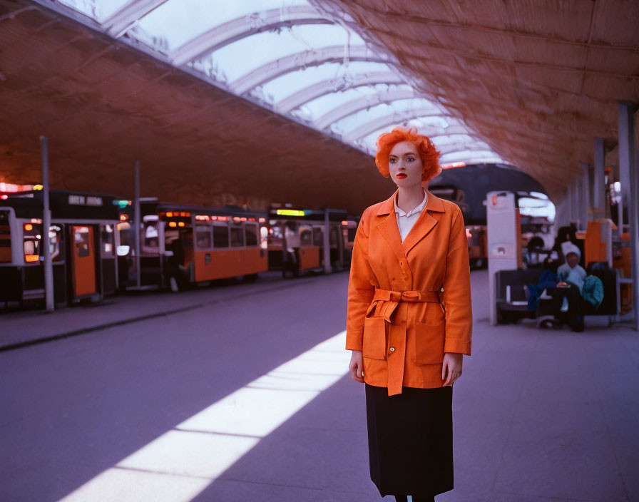 Vibrant orange-haired woman at train station with bright orange jacket