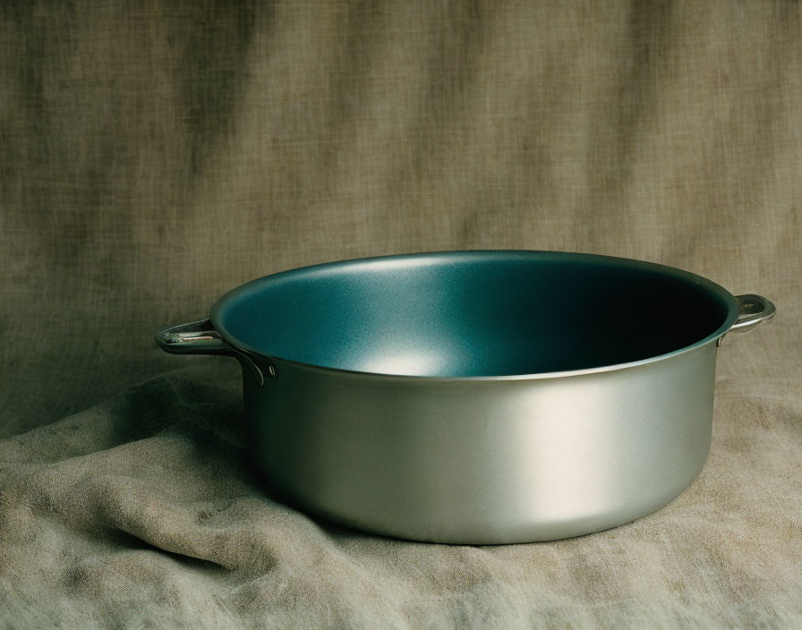 Silver Metal Roasting Pan with Handles on Beige Cloth on Taupe Background