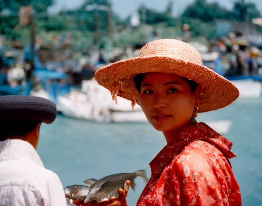 Woman in red blouse with fish by coastal village