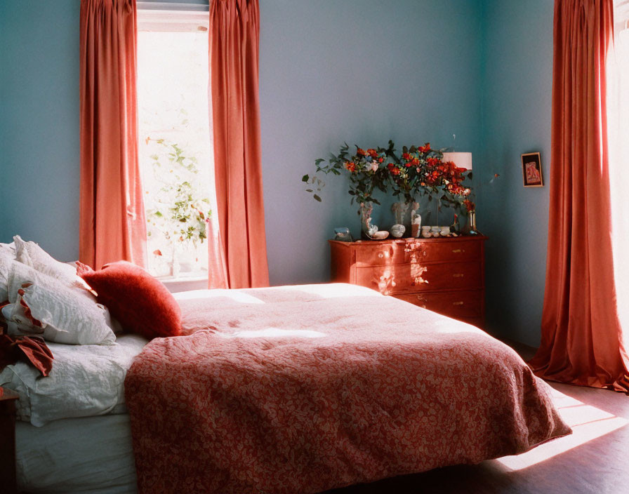 Warmly lit bedroom with red blankets, matching curtains, and floral decor