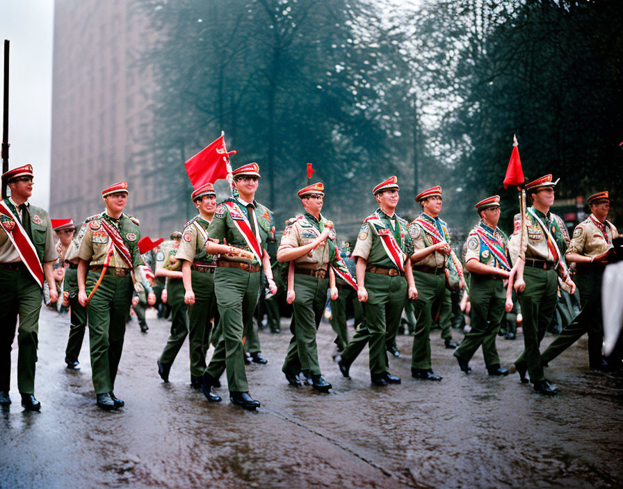 Boy Scouts marching with flags on wet street in misty cityscape