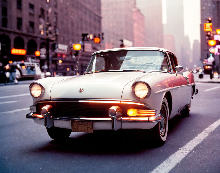 Classic car with unique tailfins in urban setting with traffic lights and crosswalks.