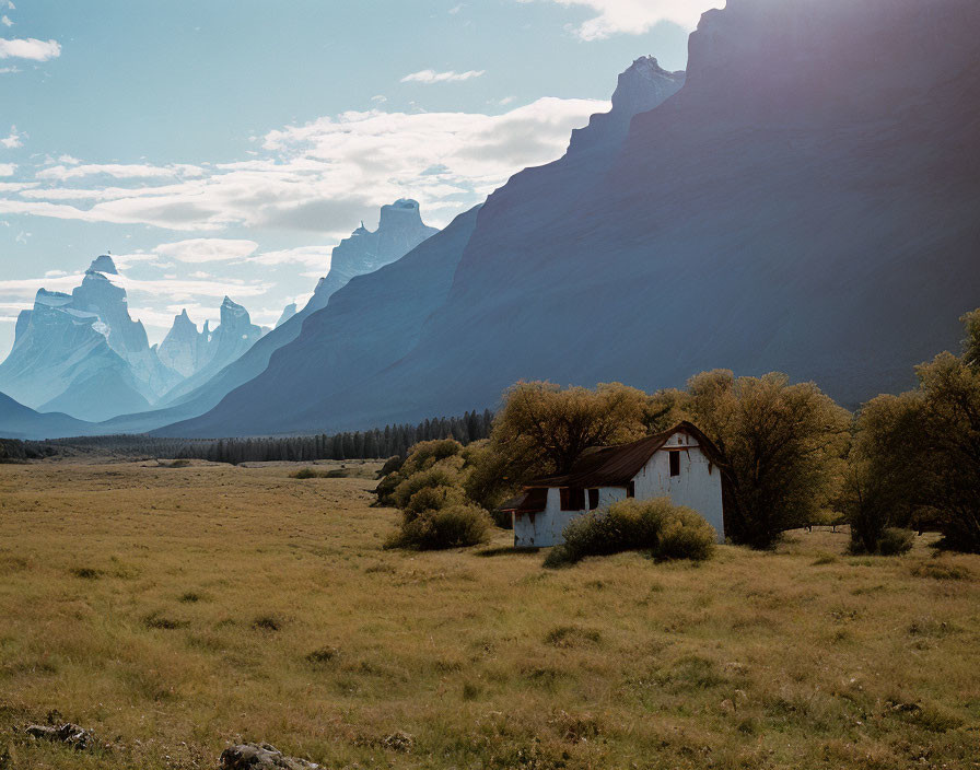 White House with Red Roof in Meadow Surrounded by Autumn Trees and Mountains