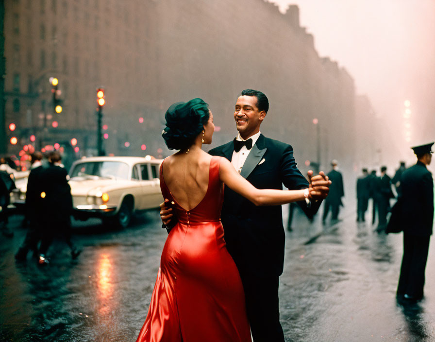 Couple dancing in formal attire on city street at dusk with vintage cars and street lights in background.