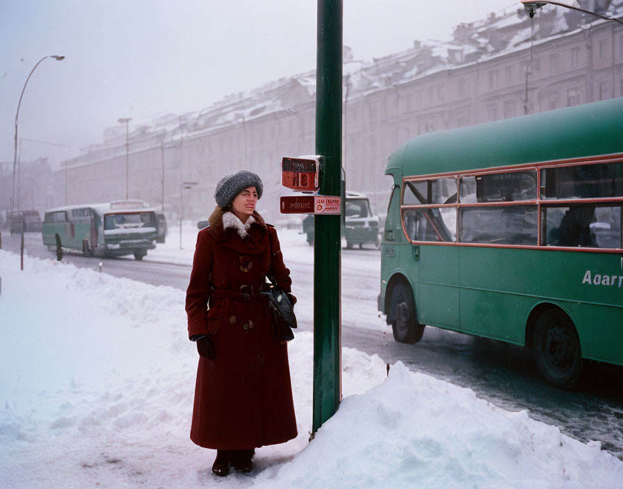 Woman in red coat and fur hat at snowy bus stop with green bus and vehicles.