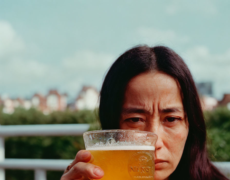 Person looking skeptically over beer glass with city skyline and cloudy skies