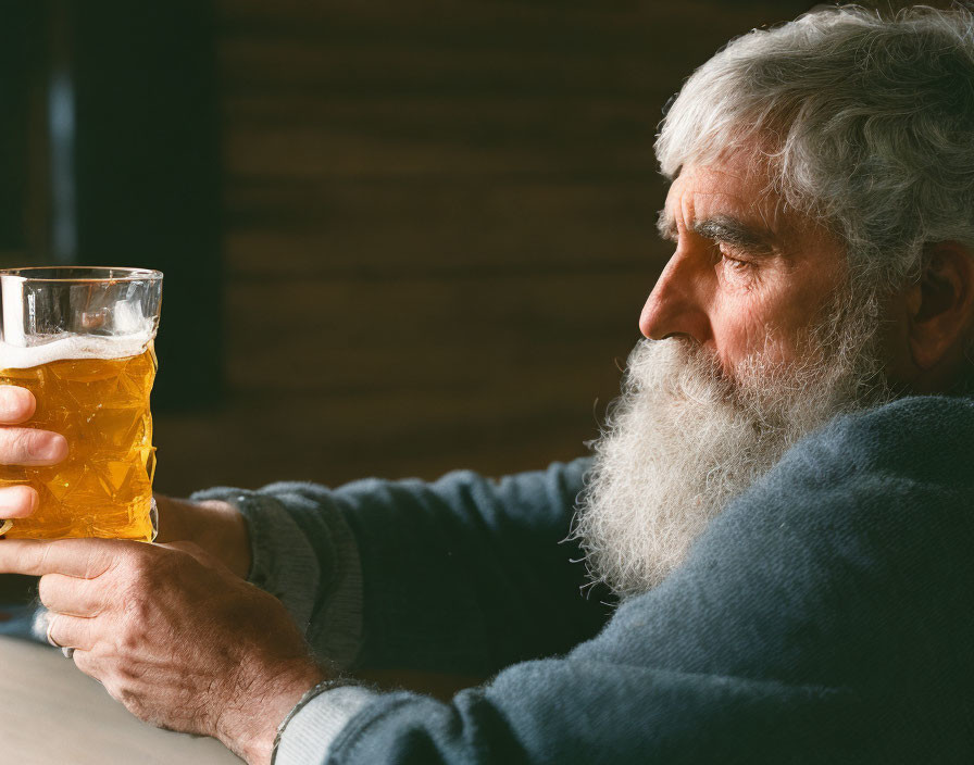 Elderly man with white beard and beer in warm setting