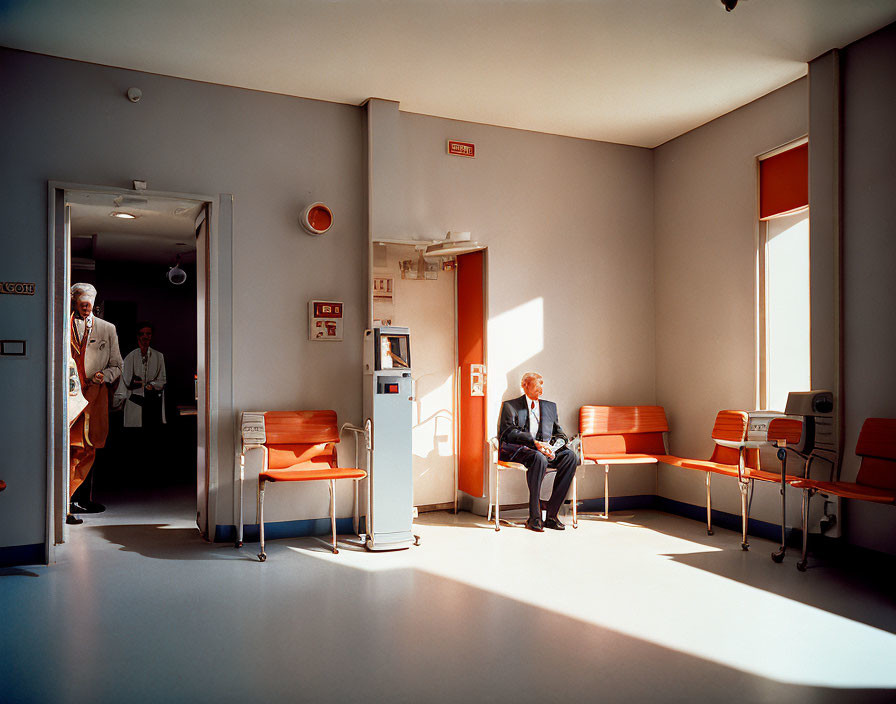 Bright waiting room with elderly man, orange chairs, sunlight, and person in white coat.