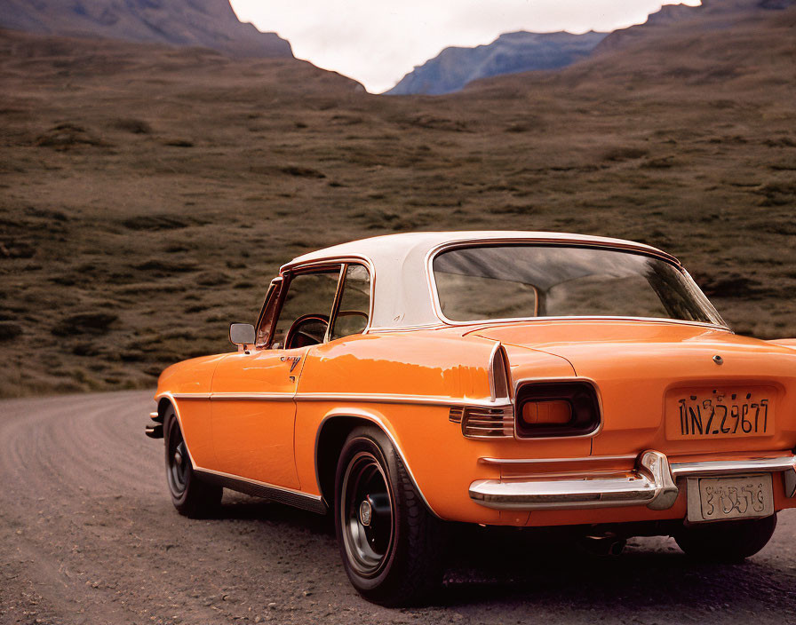 Vintage Orange Car on Winding Road with Mountains