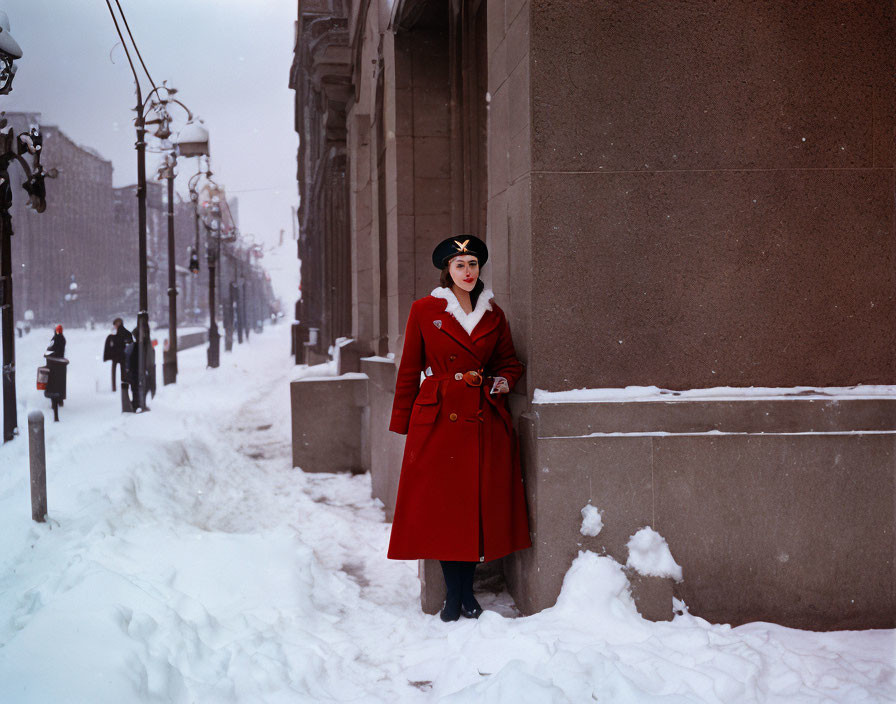 Woman in red coat and black hat against snowy city backdrop