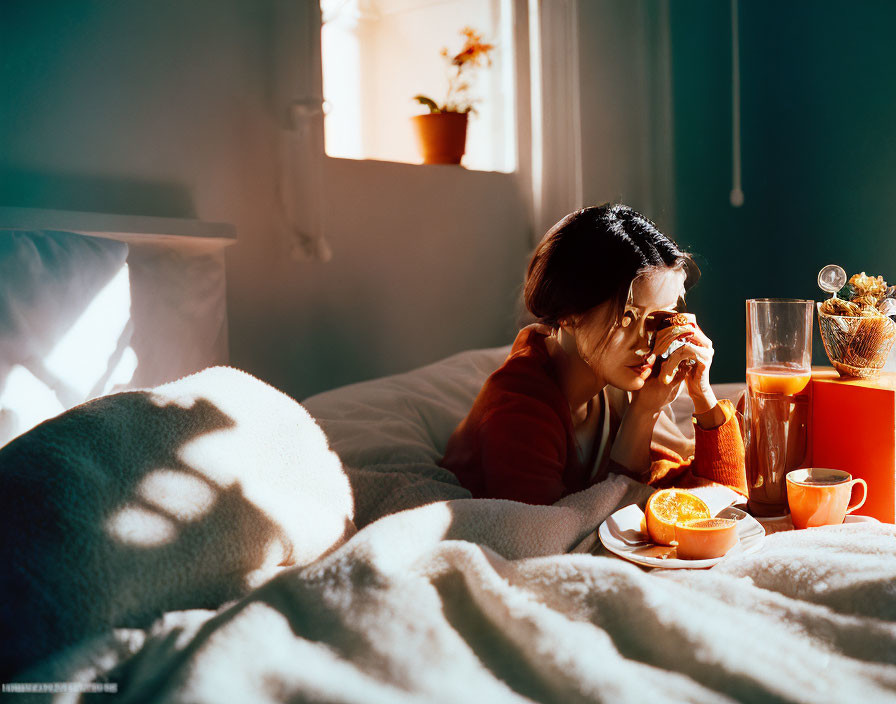 Person sitting on bed with breakfast tray in sunlit room