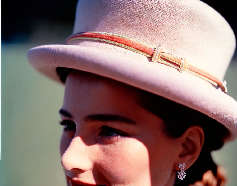 Smiling woman in pale hat with ribbon detail, close-up shot