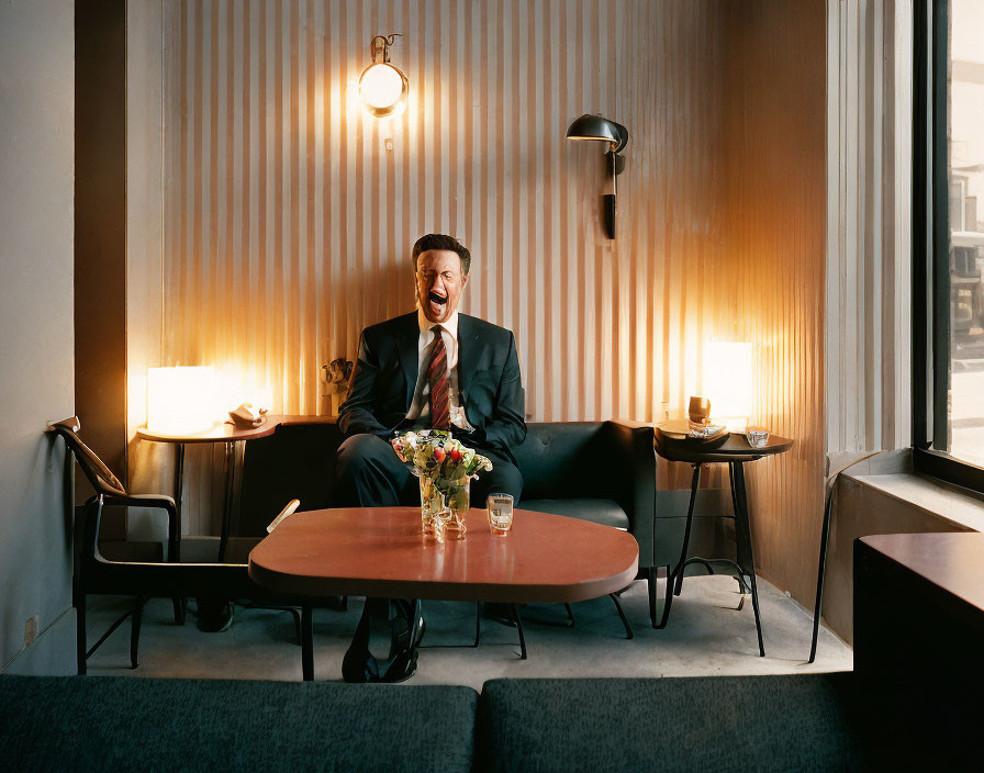 Man in suit laughing at table in stylishly lit room