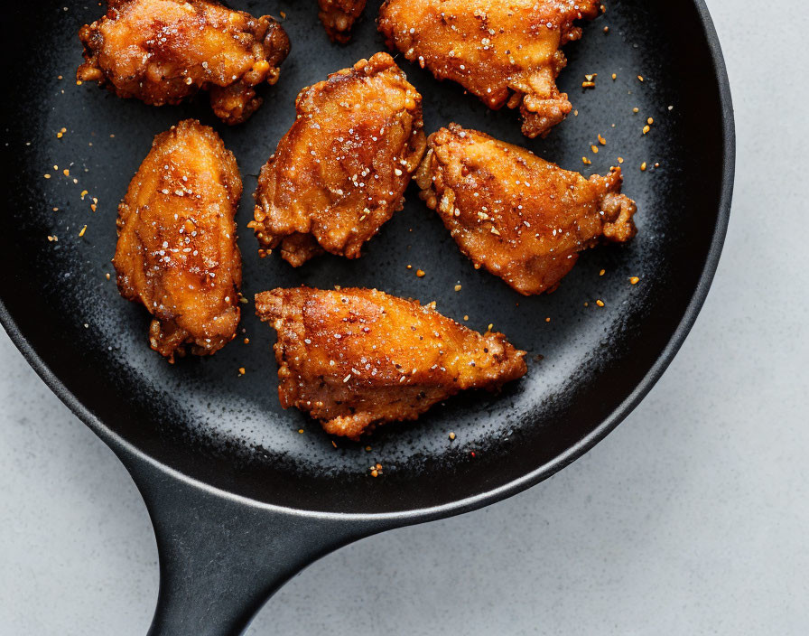 Crispy fried chicken wings in black skillet