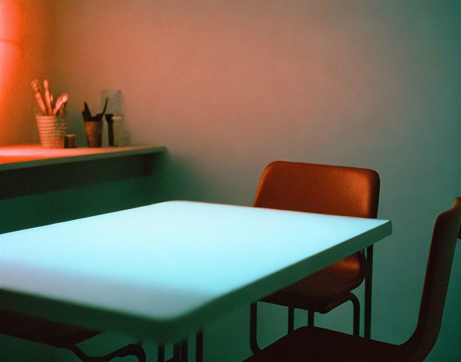 Warmly lit room with white table, brown chair, and utensils on shelf.