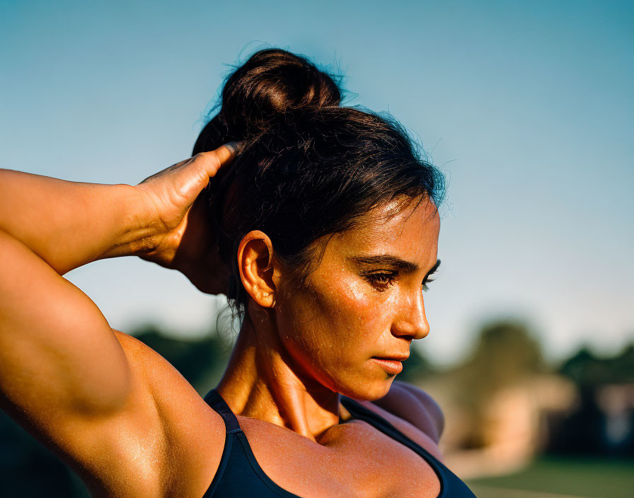 Portrait of woman with tied-up hair and tank top at sunset