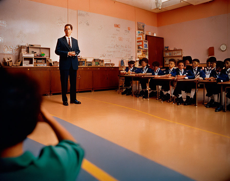 Classroom scene: Teacher instructs uniformed students at desks