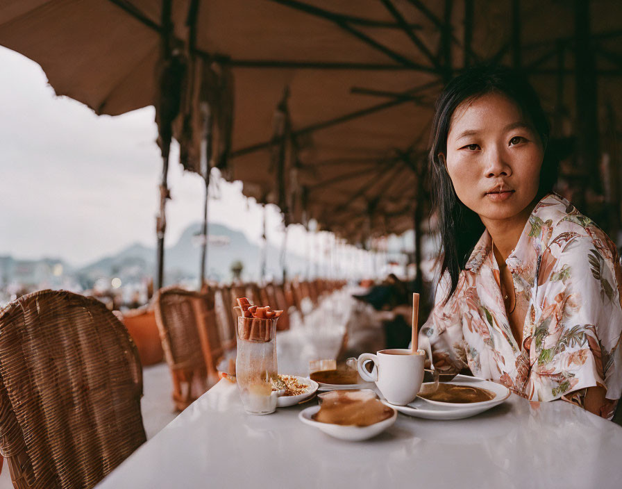 Woman at Outdoor Cafe Table with Coffee Cup and Waterfront View