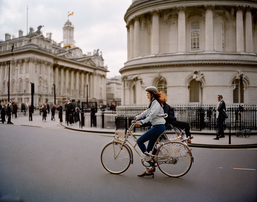 Woman in helmet biking by neoclassical government building.