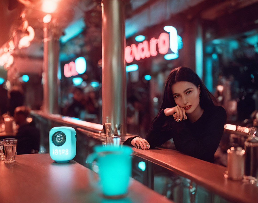 Woman in black outfit at bar counter with neon signs and blue drink.