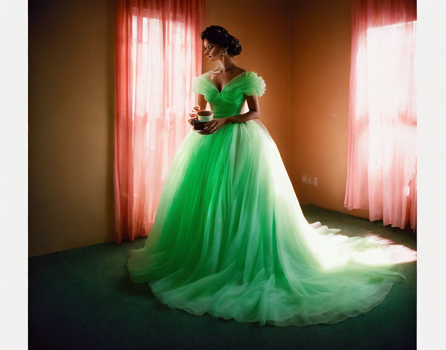 Woman in green dress by window holding teacup in sunlight