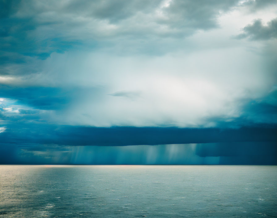 Dramatic ocean scene with stormy sky and sunlight piercing through clouds