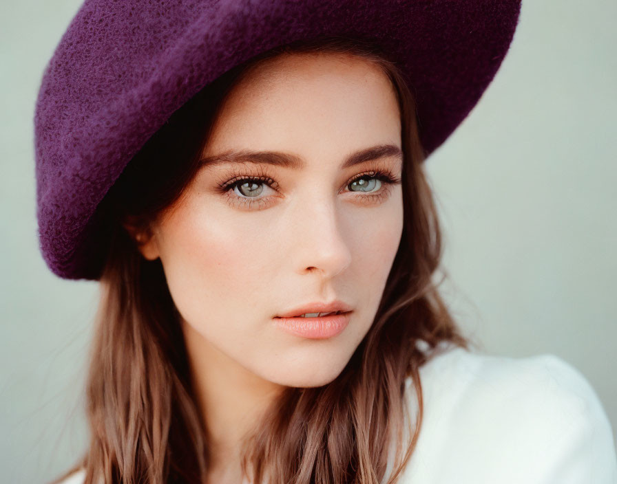 Portrait of person with fair skin and light eyes in purple hat and subtle makeup