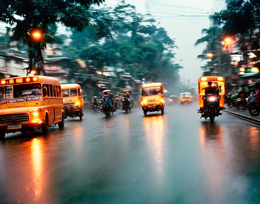 City street scene with vehicles and motorbikes on wet road at night.