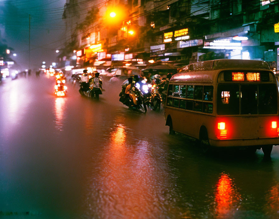 Night scene of vehicles navigating waterlogged street with illuminated headlights in urban setting