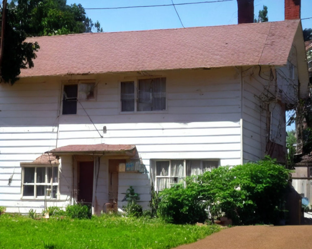 Neglected white house with pink roof and overgrown greenery