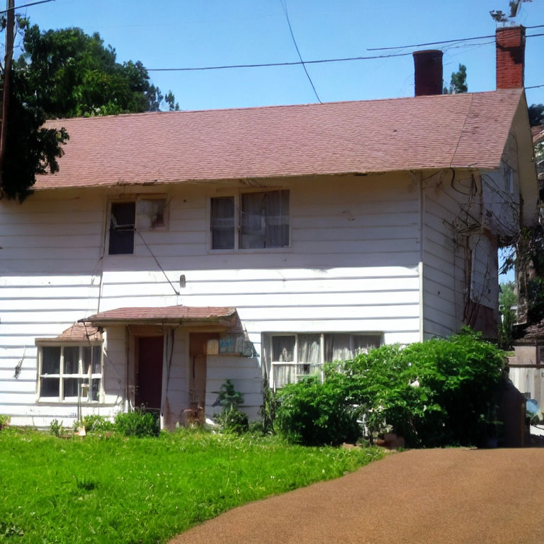 Neglected white house with pink roof and overgrown greenery