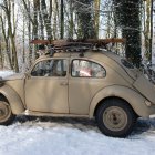 Vintage Car with Intricate Designs in Snowy Landscape with Bare Trees