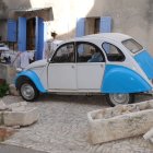 Vintage Blue Bus Parked in Front of Quaint House with Blossoming Trees