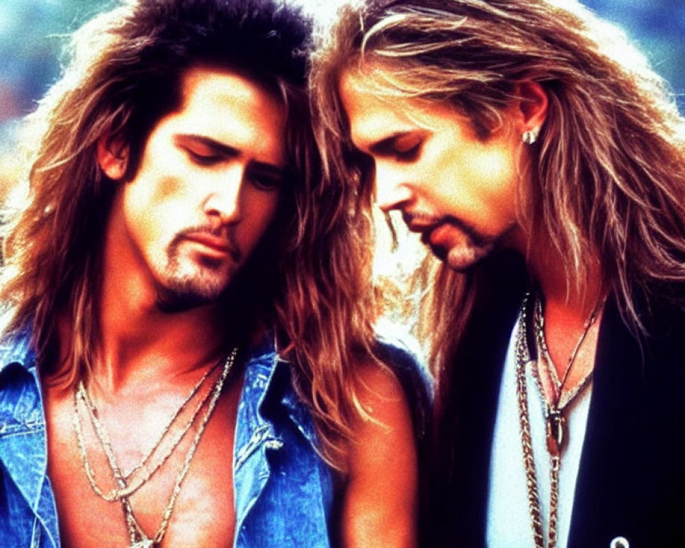 Two individuals with long, styled hair and denim outfits in a classic rock appearance.