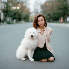 Young woman with white dog on street with trees and houses.