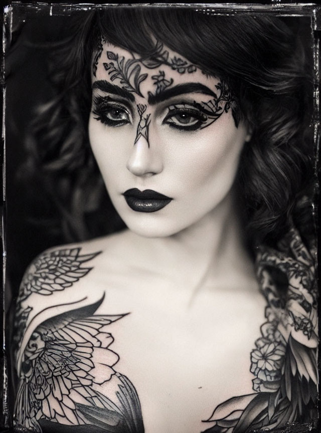 Monochrome portrait of a person with intricate tattoos and bold makeup